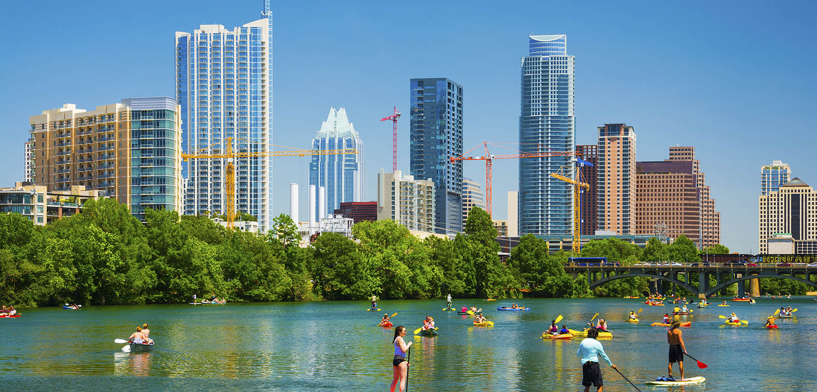 Austin, United States - May 3, 2014 - People having fun on rowboats and boards in Lady Bird Lake on a nice day with the Austin skyline in the background.